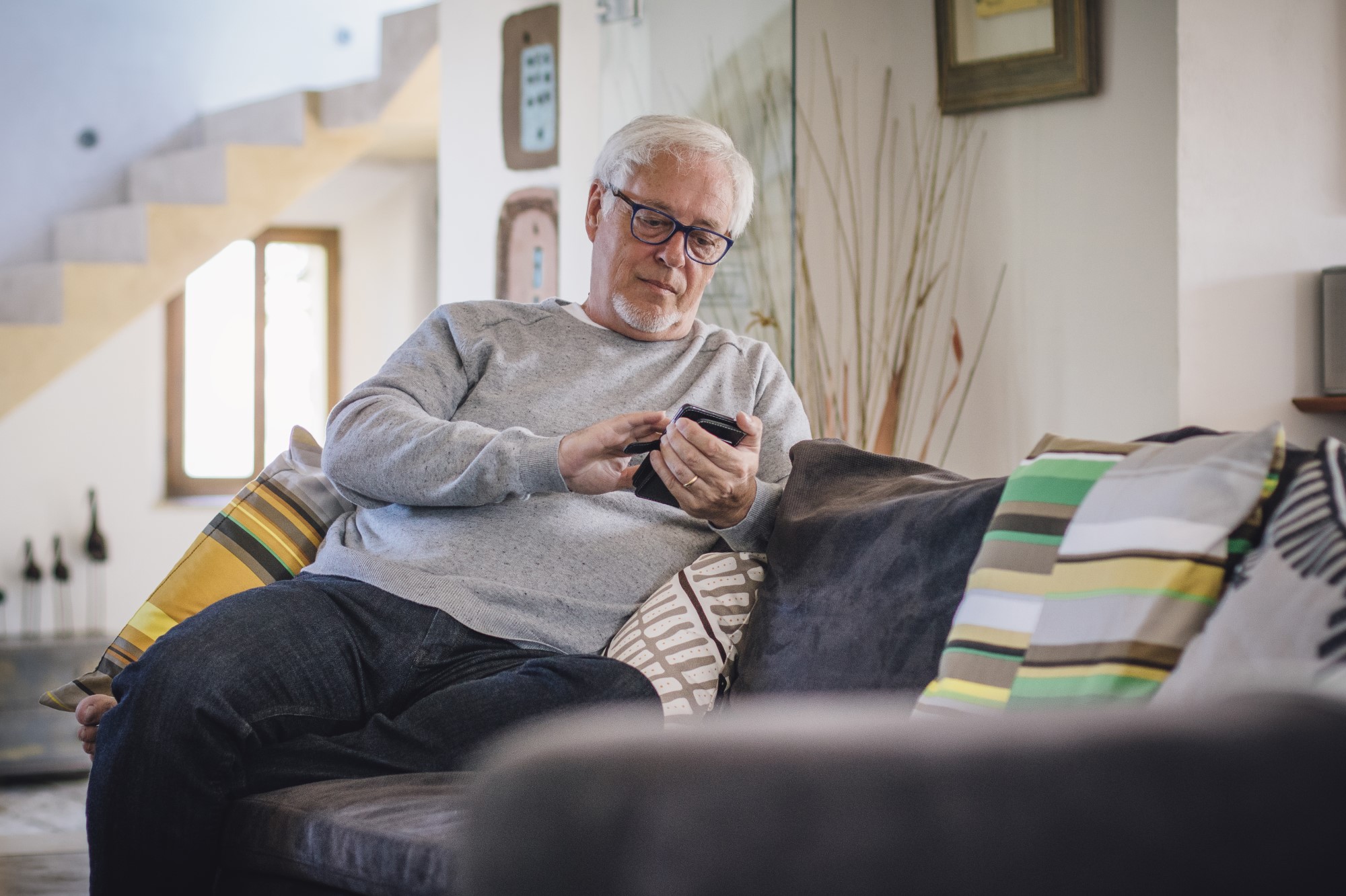 Older man sitting on couch looking at mobile phone