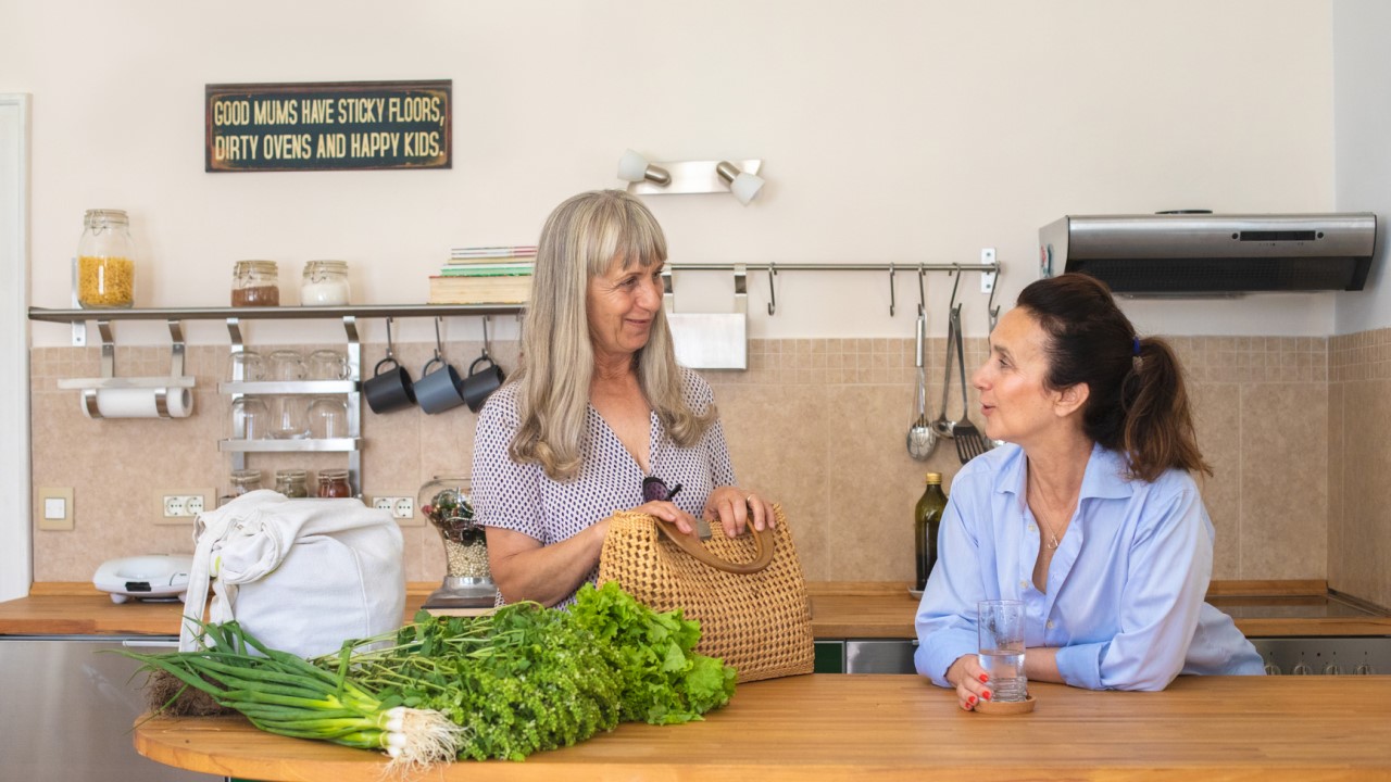 Younger woman talking to older woman in kitchen