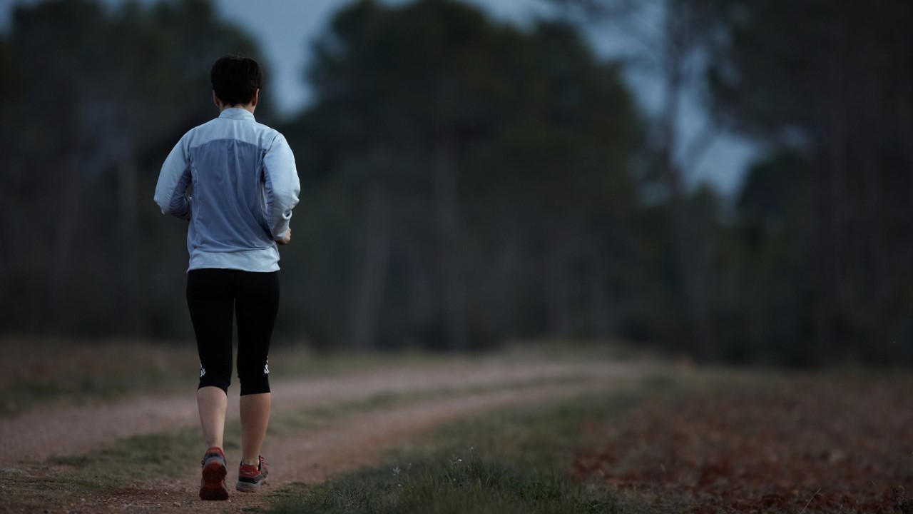 Older man running along dark road