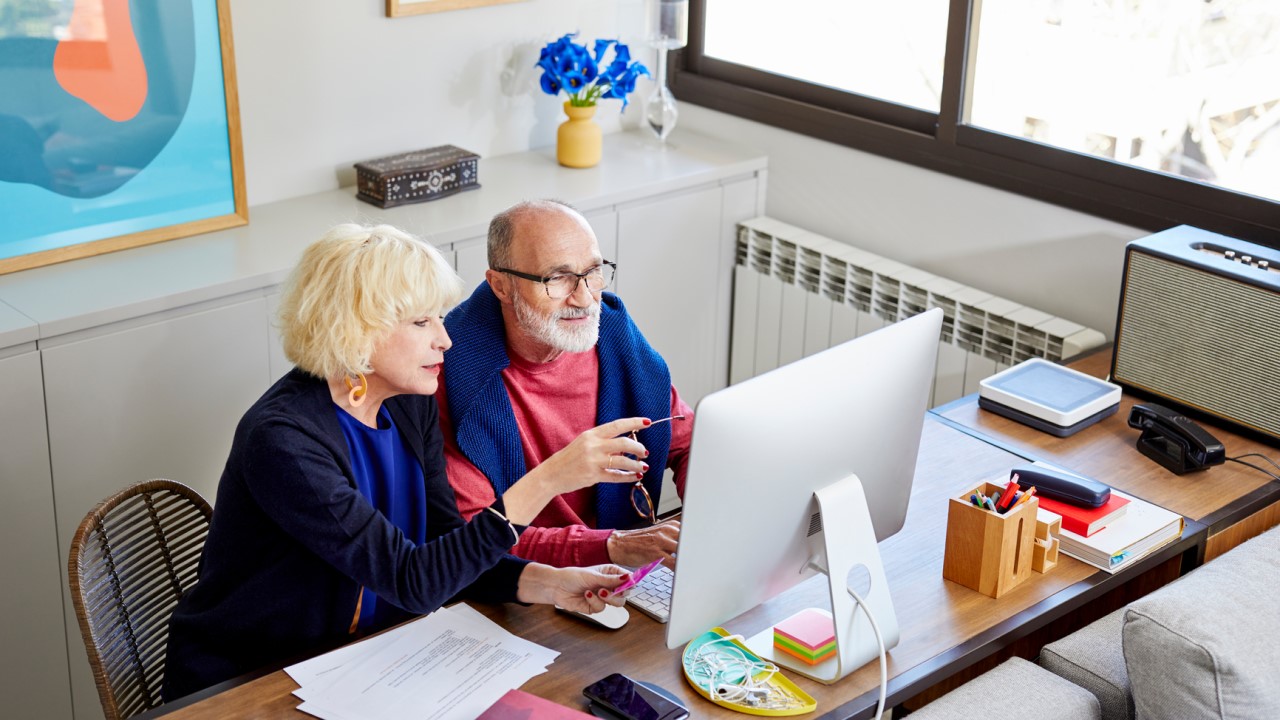 Older woman and man looking at computer screen in home office