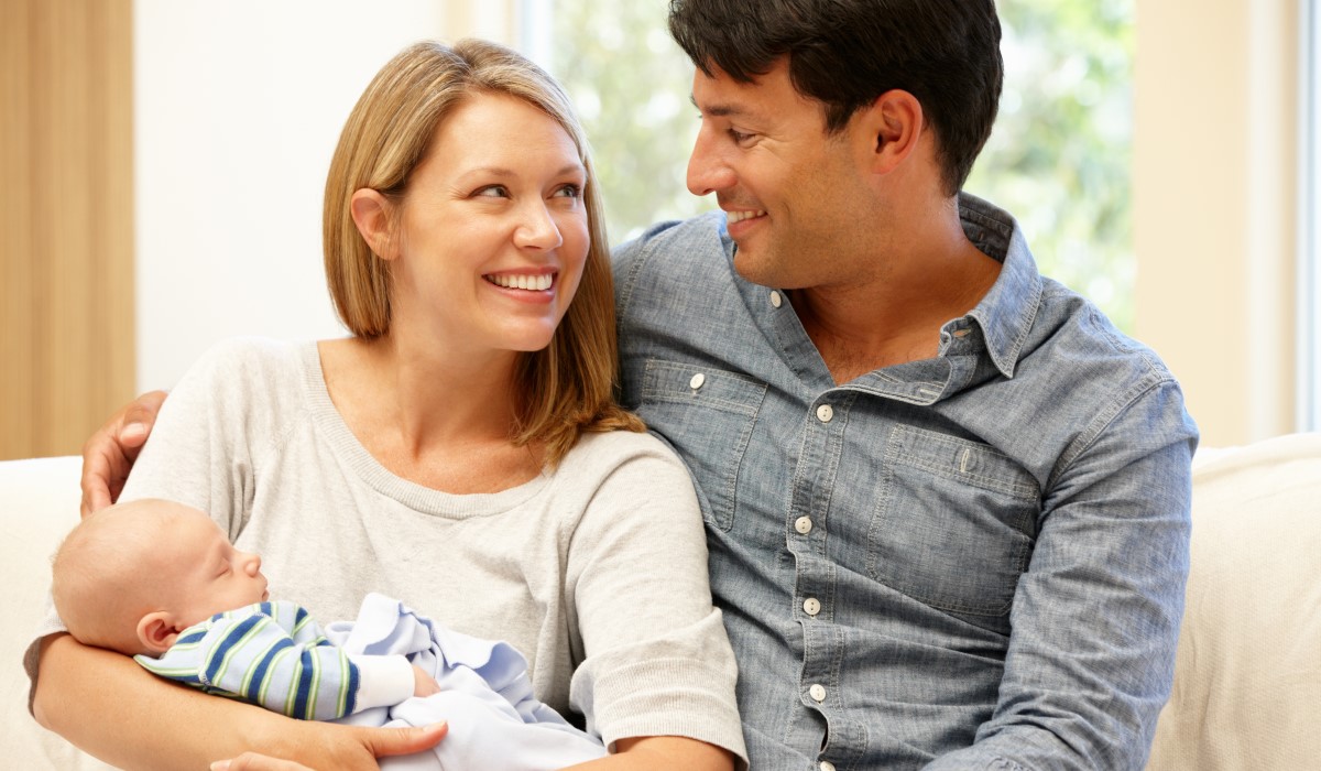 Mother holding newborn with partner 