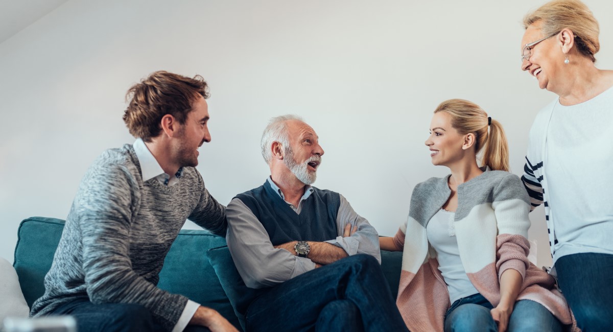 Adult man and woman laughing with older parents