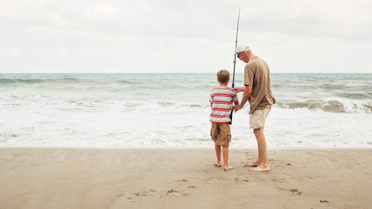 Man and boy fishing on a surf beach