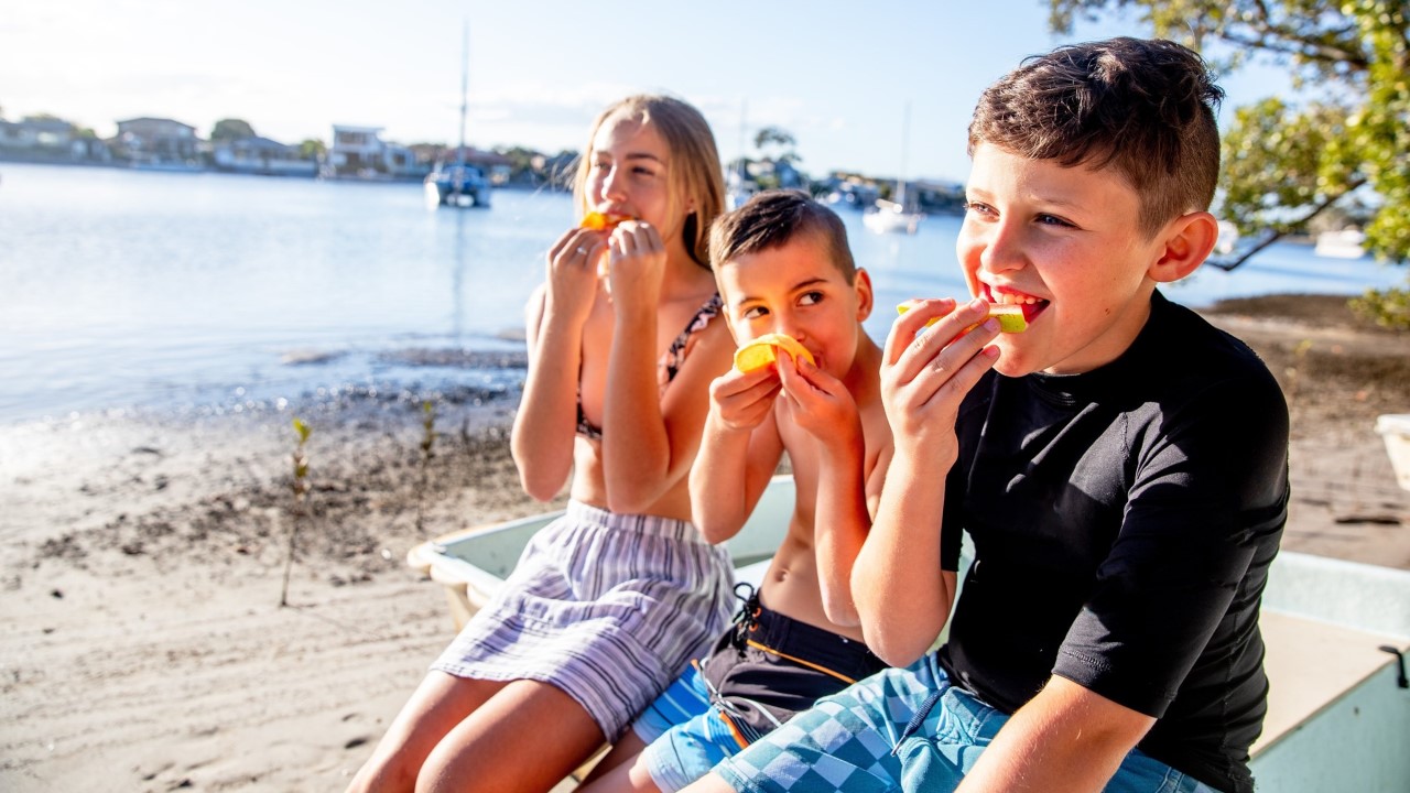 Kids at beach eating fruit