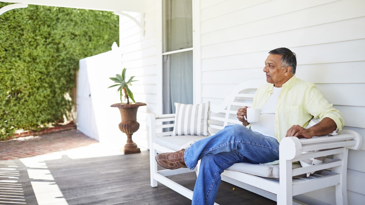 Older man sitting on a bench seat on porch