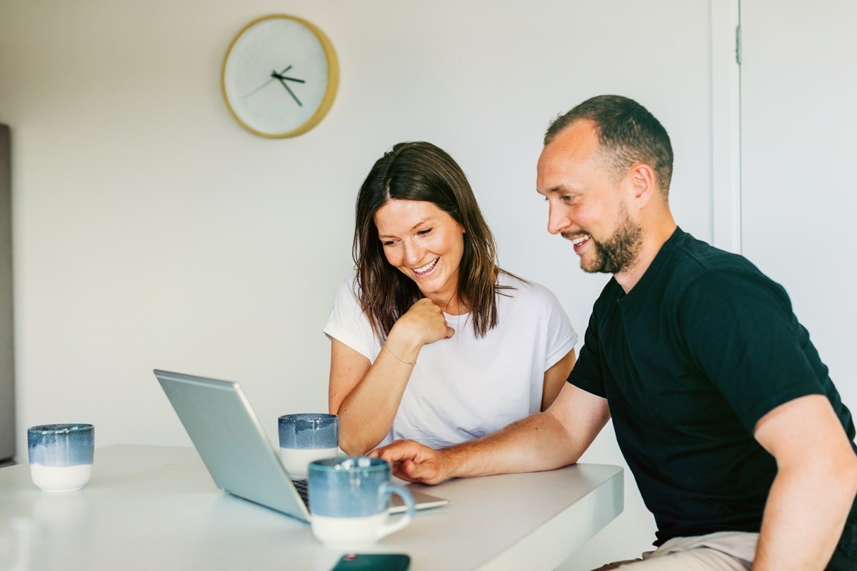 Smiling woman and man looking at laptop screen