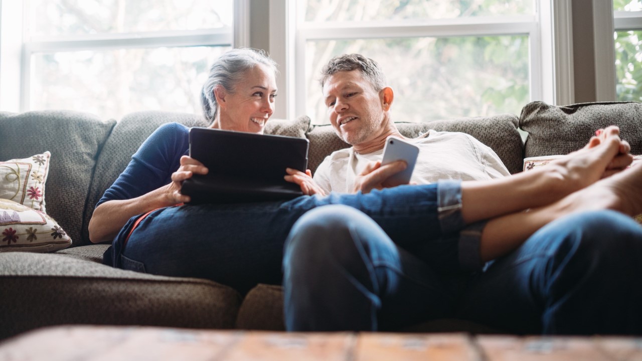 Older man and woman looking at laptop on couch