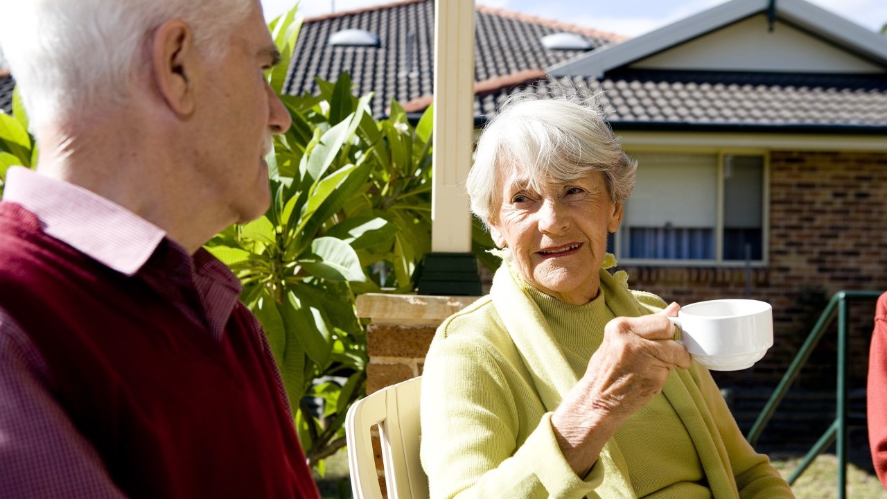 Elderly man and woman enjoying a cup of tea in the sunshine