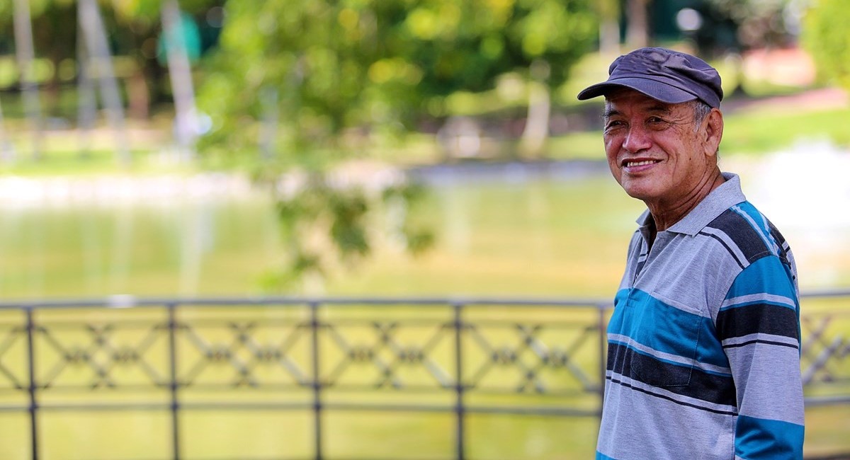 Older man smiling, looking over lake