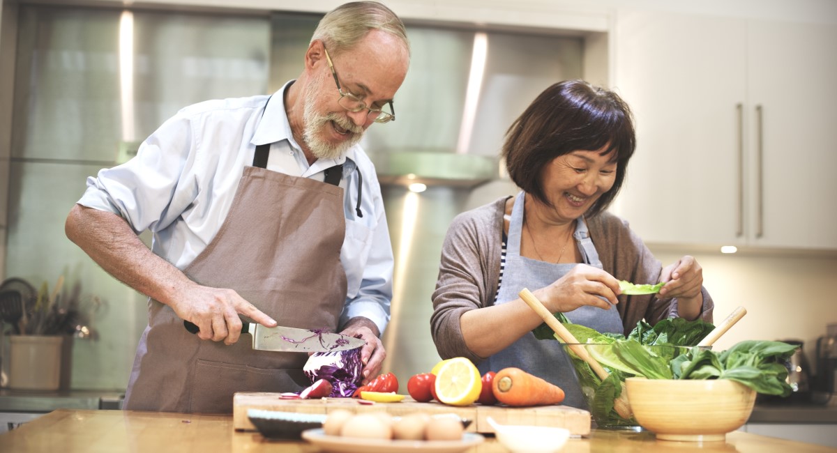 Man and woman chopping vegetables in kitchen