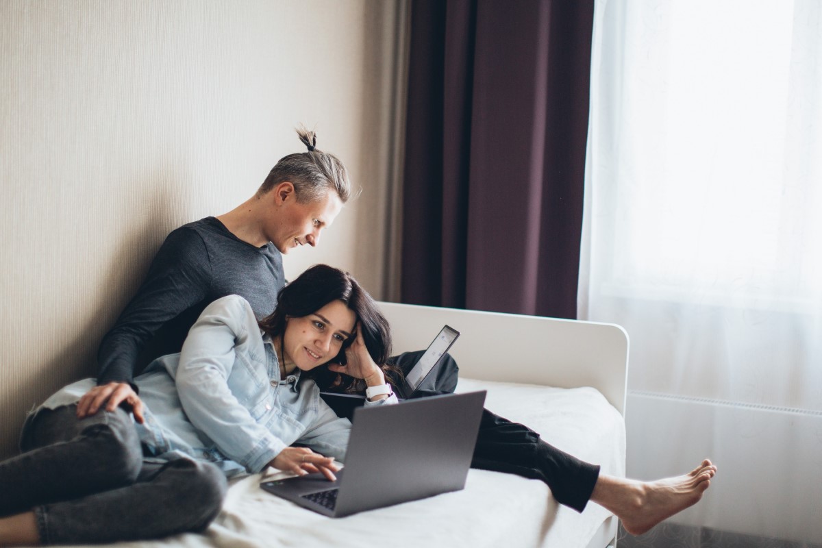 Man and woman on bed, looking at a laptop