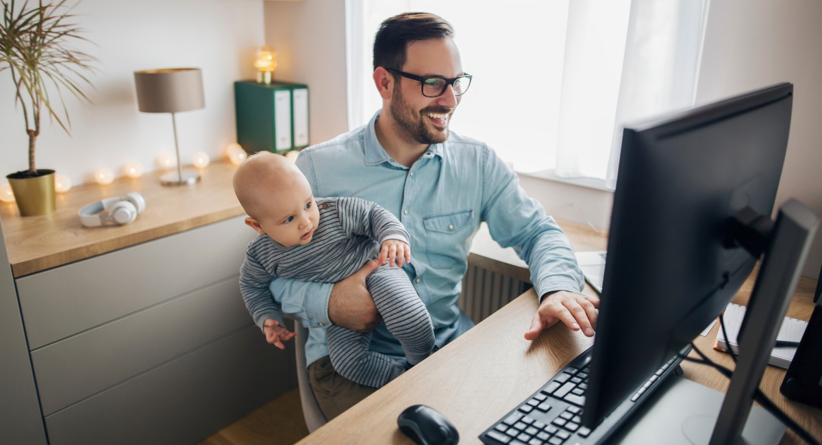 Man working from home, holding a baby