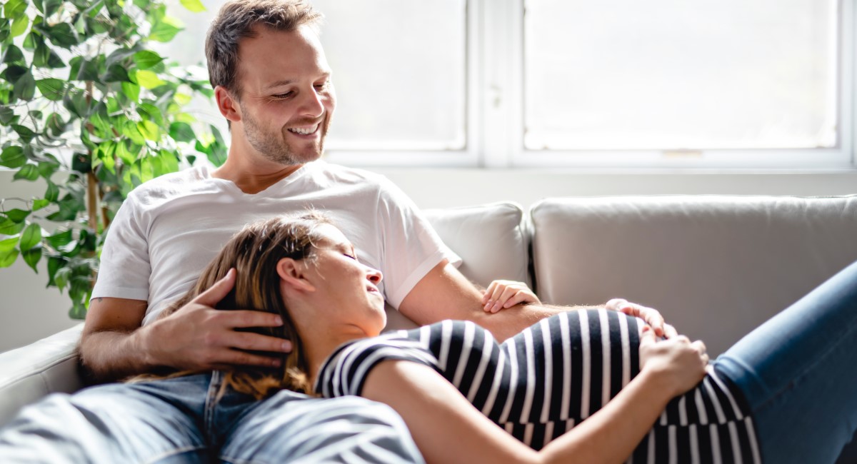 Woman leaning against man on couch, smiling and laughing