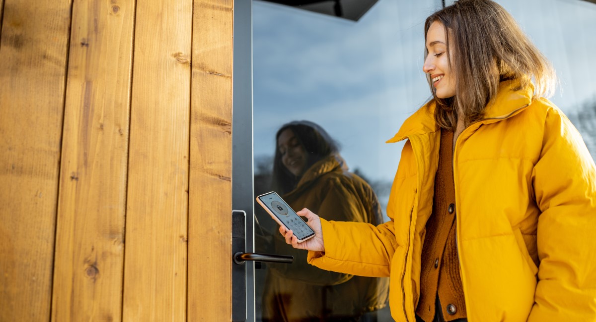 Woman locking her door with her phone