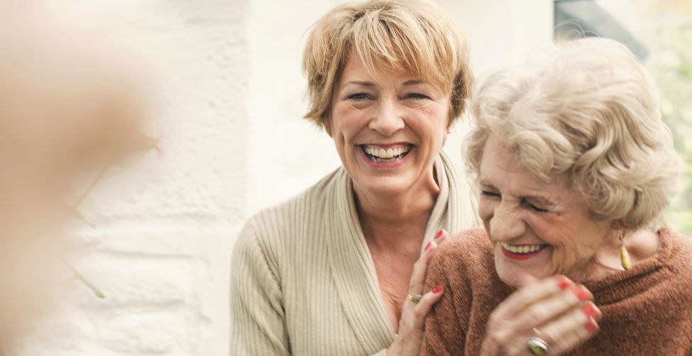 Older woman smiling and laughing with elderly woman