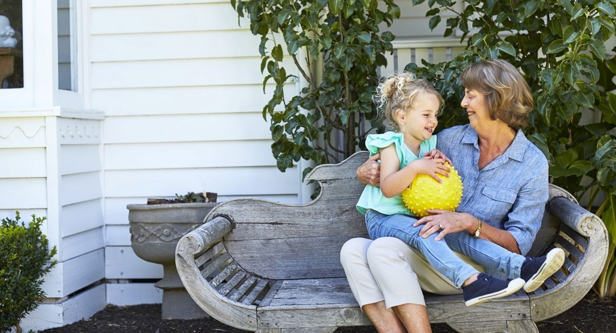 Older woman smiling, sitting with young girl