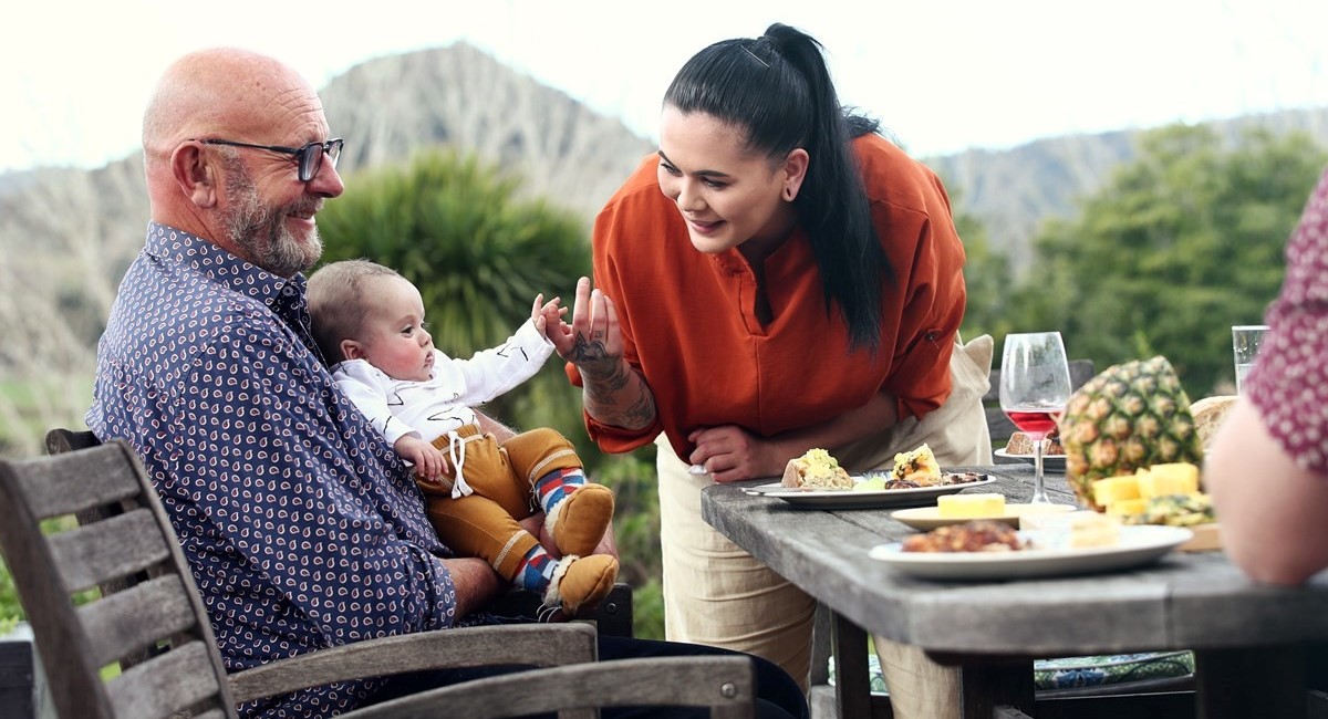 Older man holding baby at picnic table