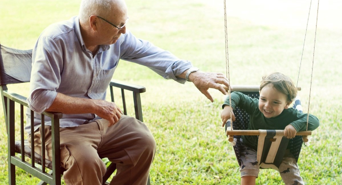 Older man pushing young boy on a swing