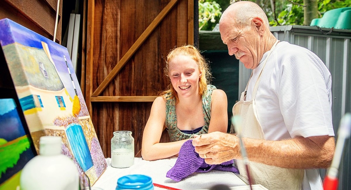 Older man painting with young girl