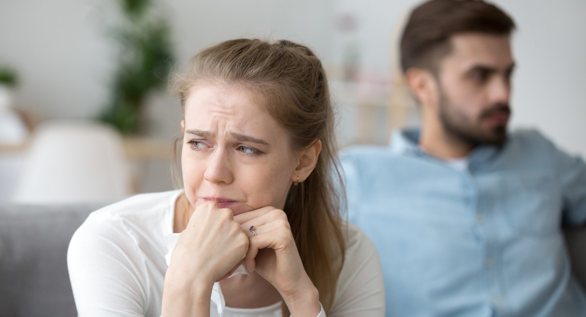 Woman looking lonely and stressed with male partner in background