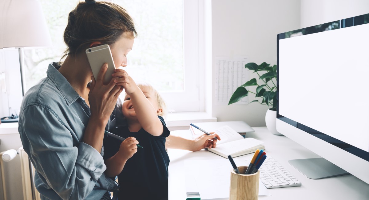 Mum holding toddler and trying to work