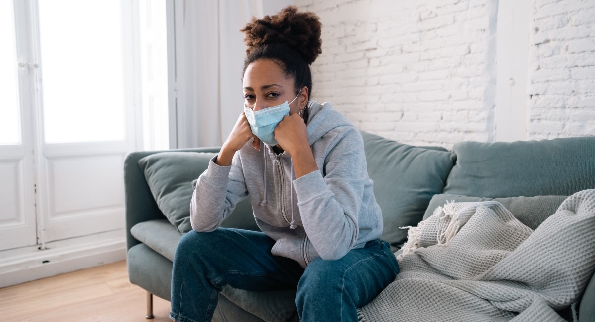 Woman in mask sitting on couch