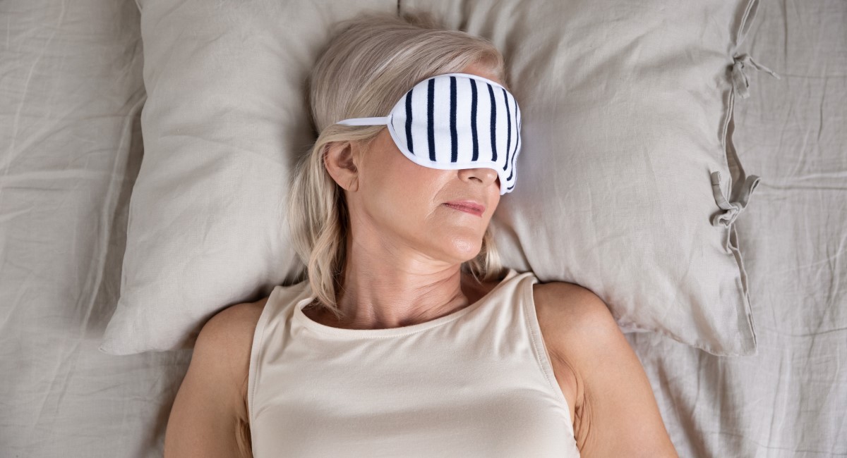 Older woman asleep in bed, wearing a sleeping mask