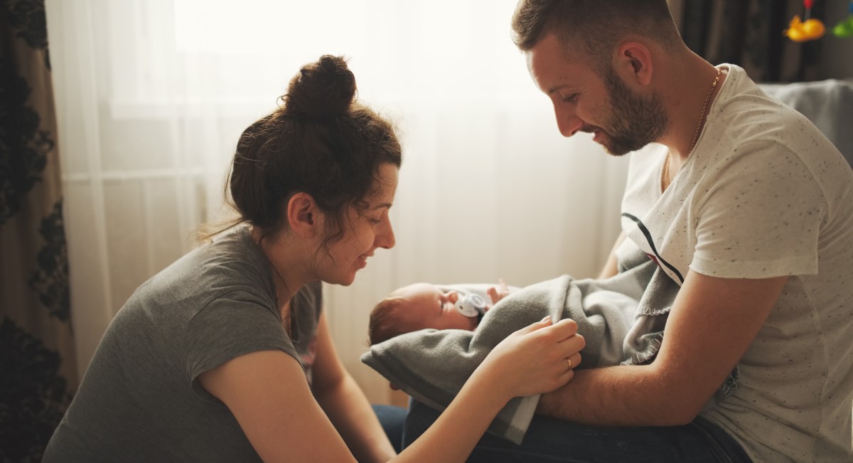 Father holding newborn with mum looking at them both