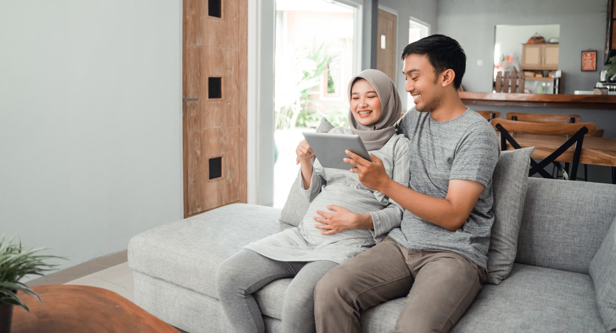 Pregnant woman and partner looking at an ipad