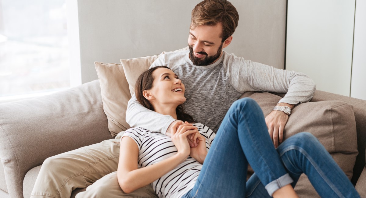 Woman leaning against man on couch, smiling and laughing