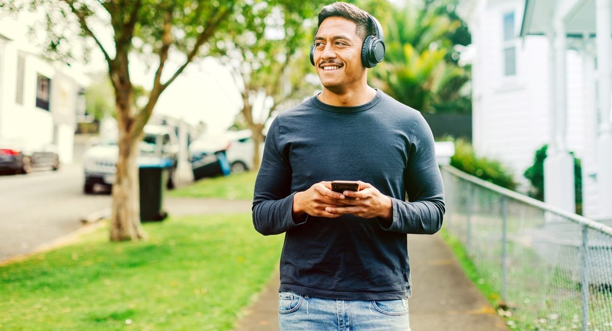 Smiling man listening to music through wireless headphones