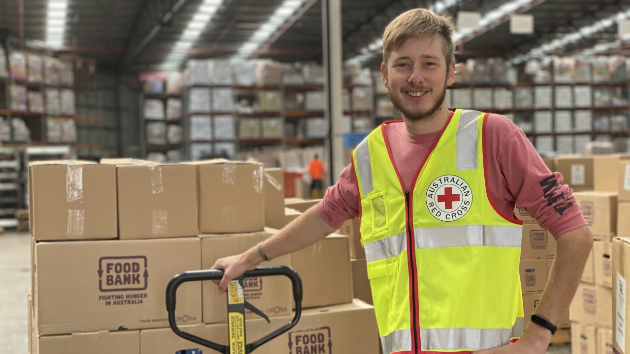Man in warehouse in high-vis Red Cross vest