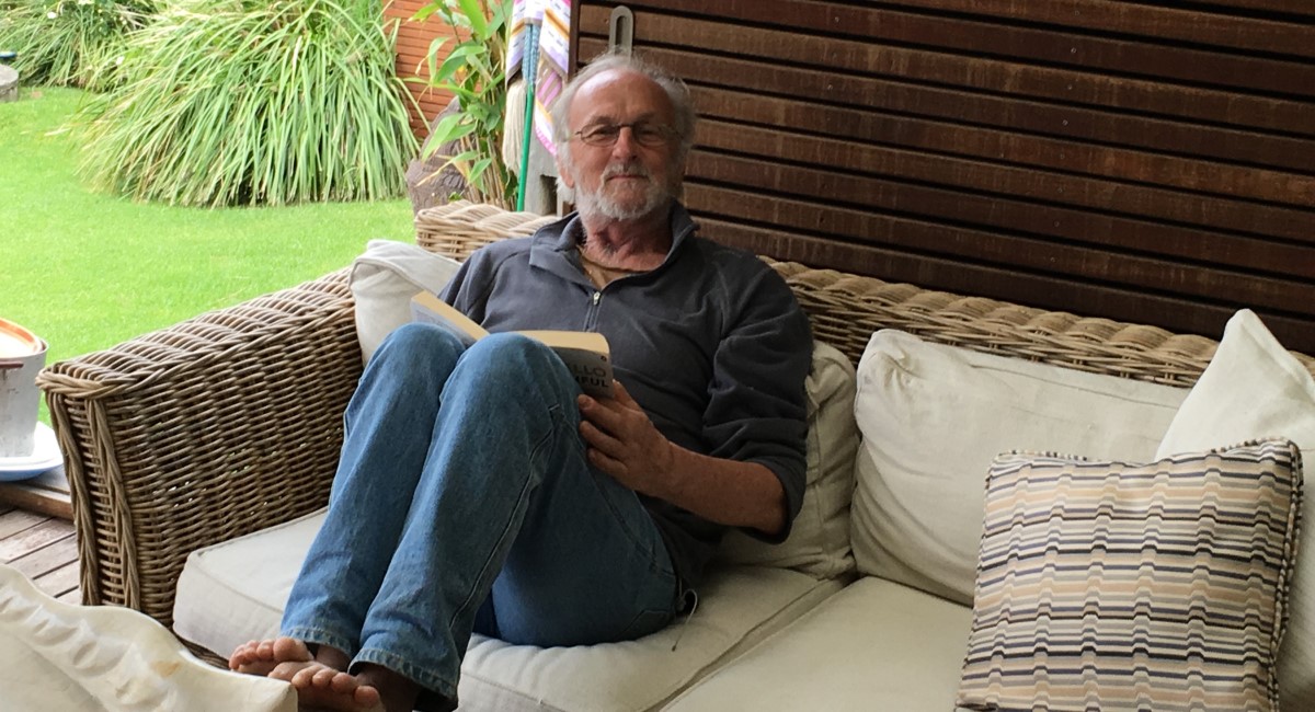 Rex Little, feet up, reading a book on the couch