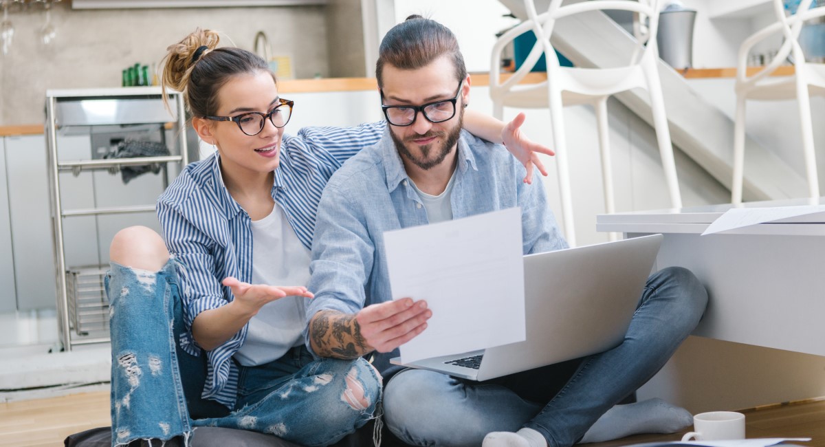 Man and woman sitting on floor looking at laptop