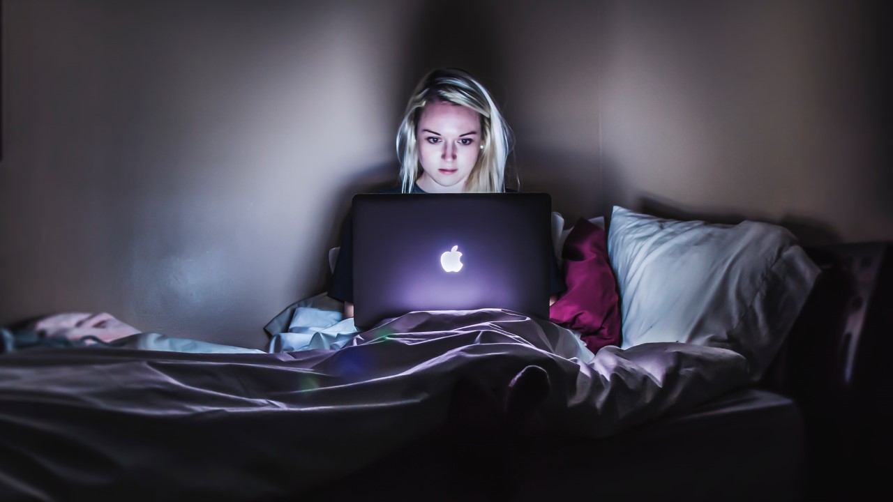 Teenage girl looking at her laptop in bedroom