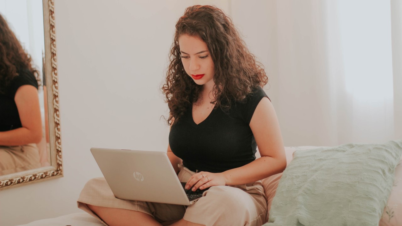 Woman working from home on laptop on bed