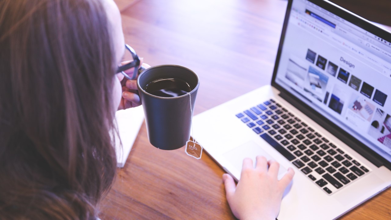 Woman sipping tea and looking at her laptop