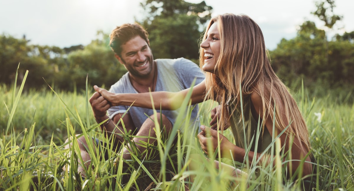Woman and man sitting in tall grass and laughing