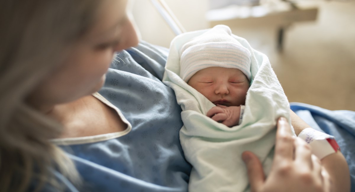 Mother holding newborn baby in hospital bed