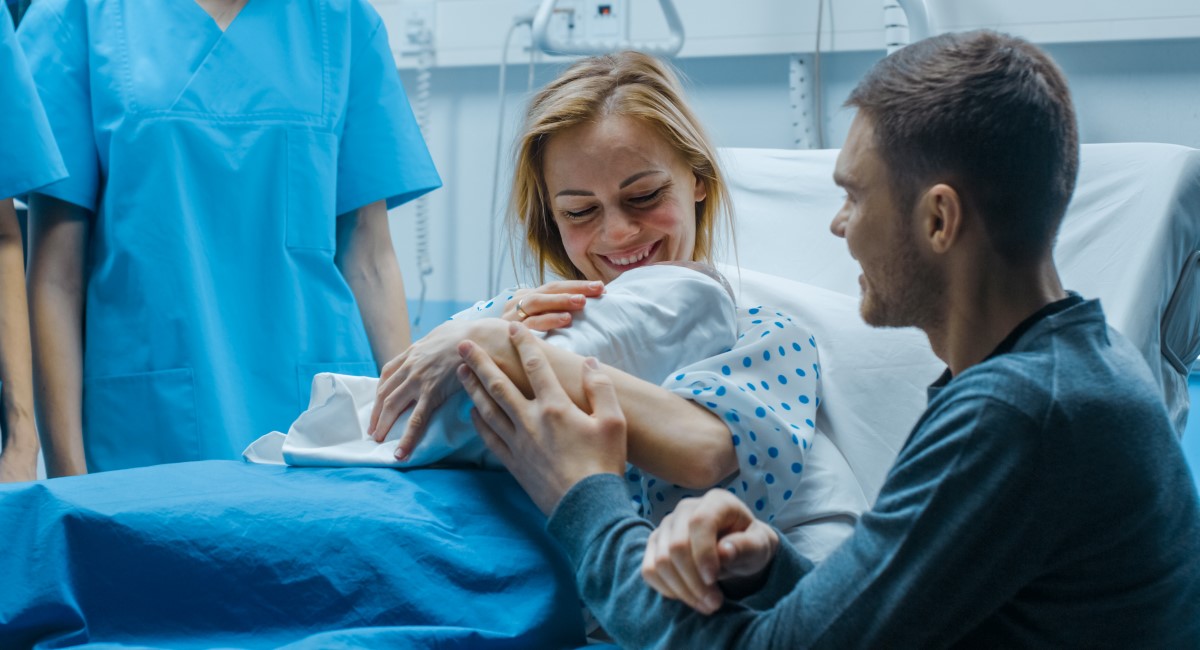 Mother holding newborn baby in hospital bed