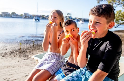 Young children eating fruit, happy at the beach
