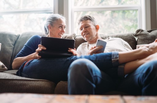 Older man and woman on couch looking at tablet