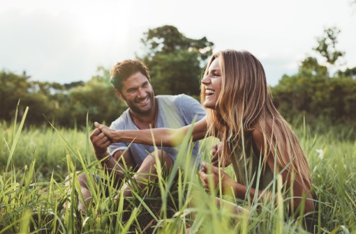 Woman and man sitting in tall grass and laughing