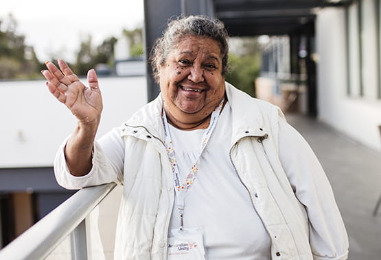 Smiling Indigenous woman looking at the camera and waving