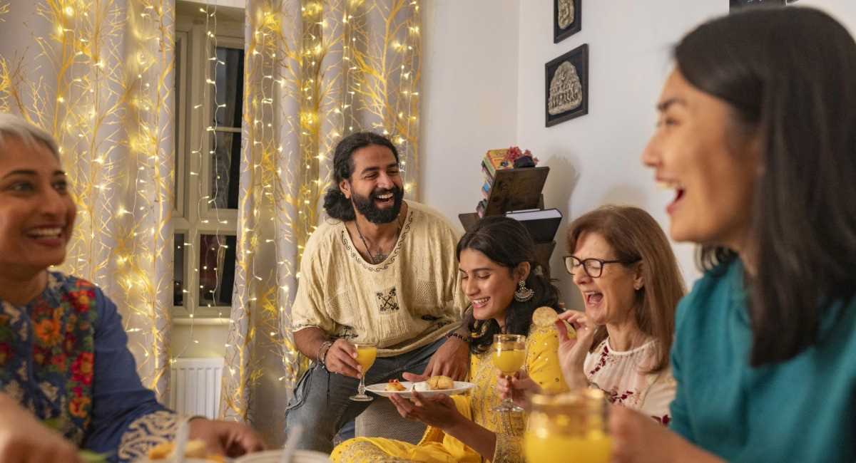 A group of middle aged friends laughing while eating dinner