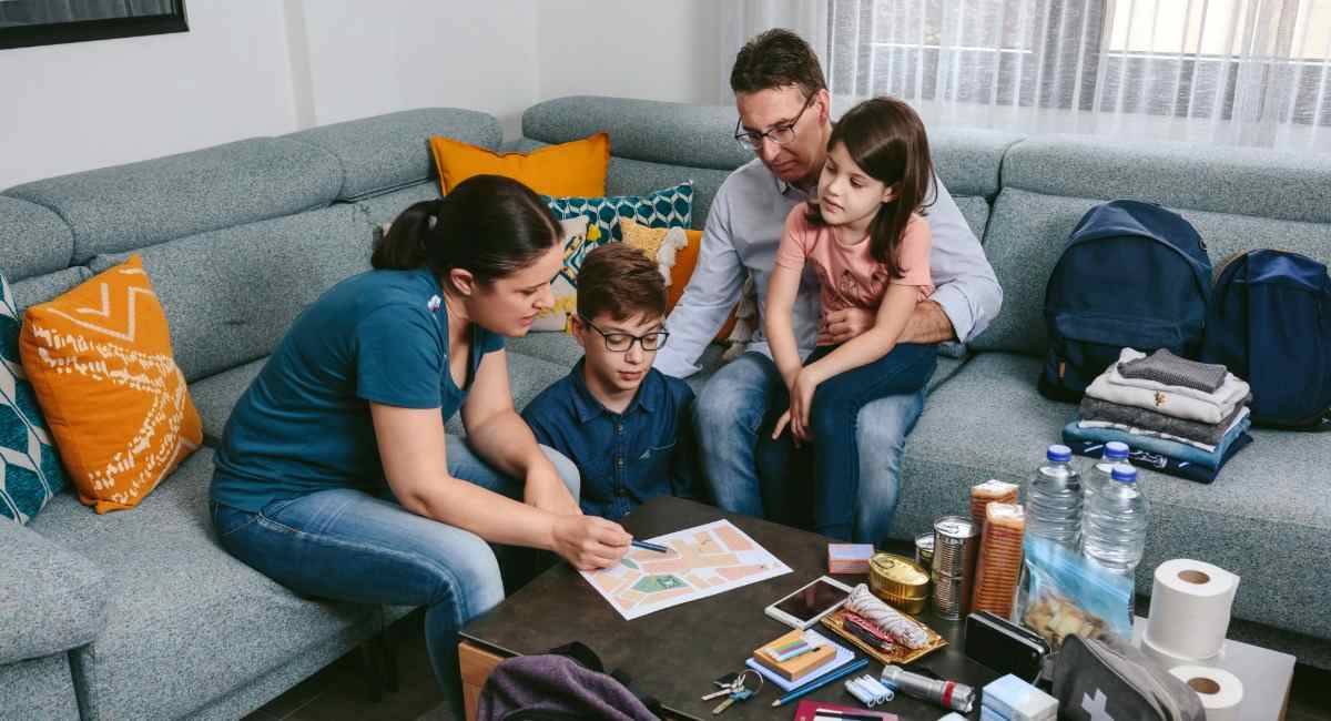 A family sitting in a lounge room consulting a fire evacuation plan