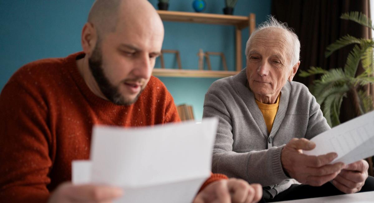 A middle aged man with his senior father looking at paperwork