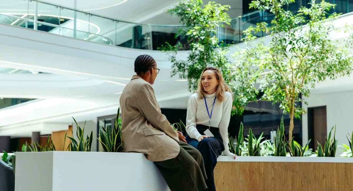 Two professional workers sitting in a modern office environment while speaking