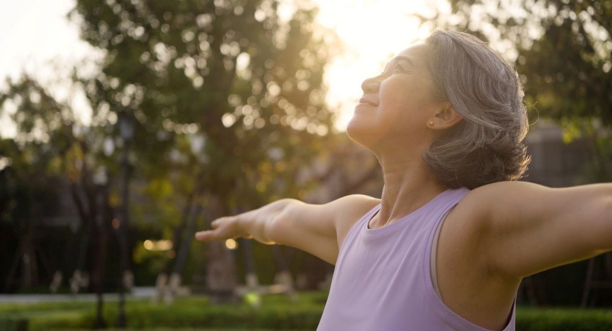 A middle aged woman in activewear looking happily into the sky