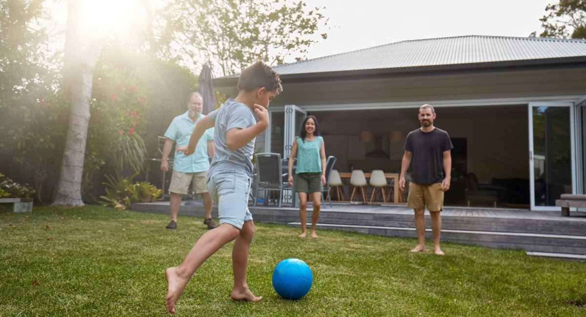 A family kicking a soccer ball in the backyard